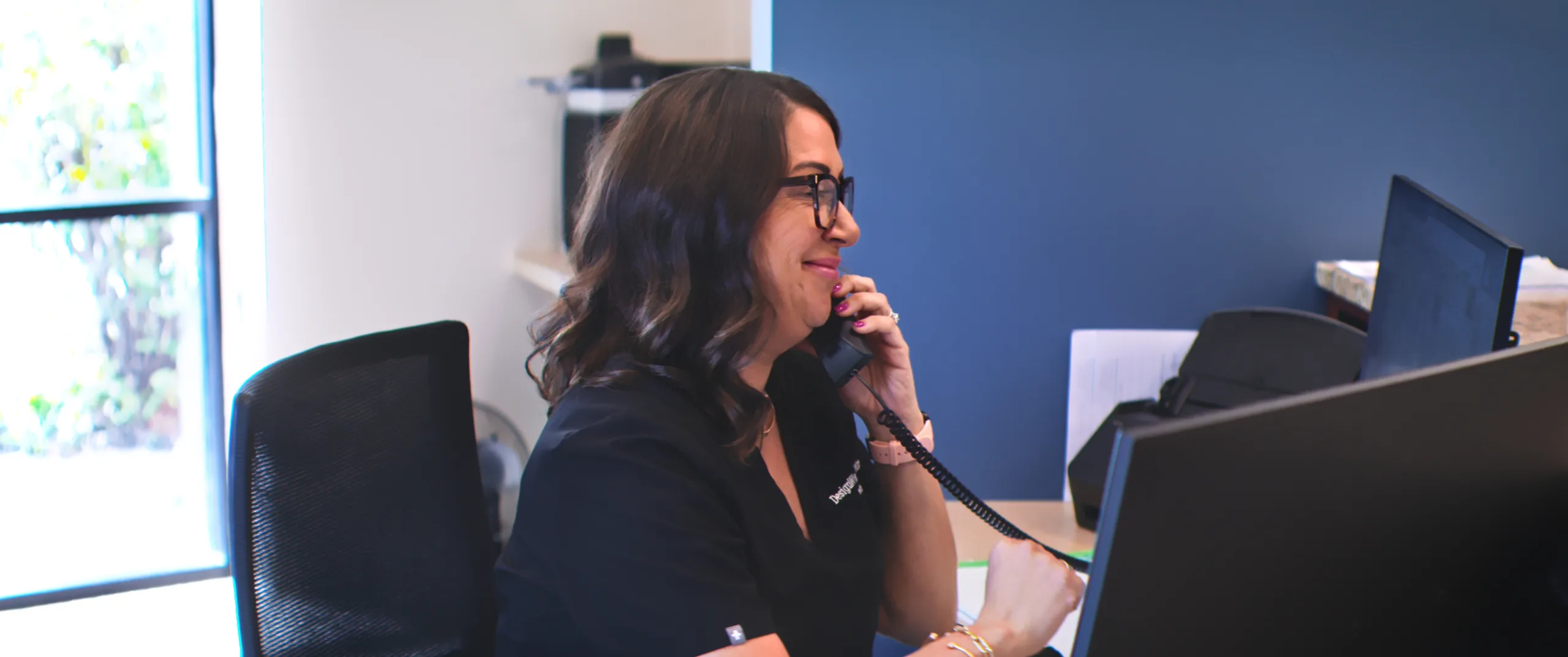 A DesignWise team member answering a phone call at reception
