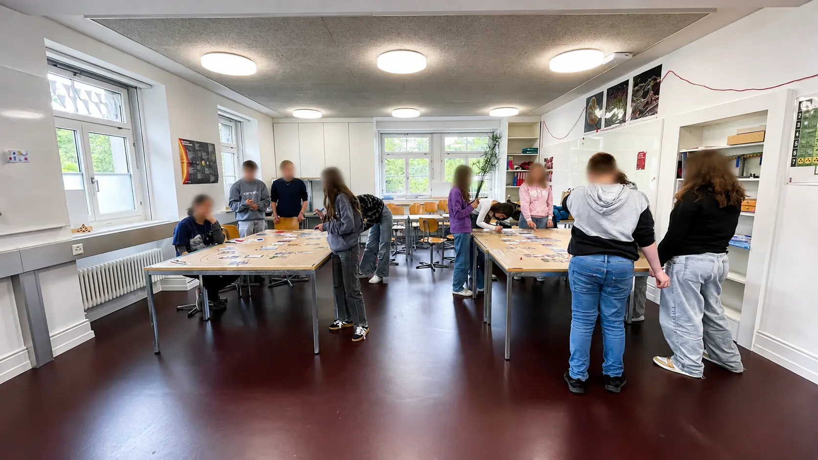 Schülerinnen und Schüler arbeiten an zwei Tischen in einem Klassenzimmer am Climate-Fresk-Workshop