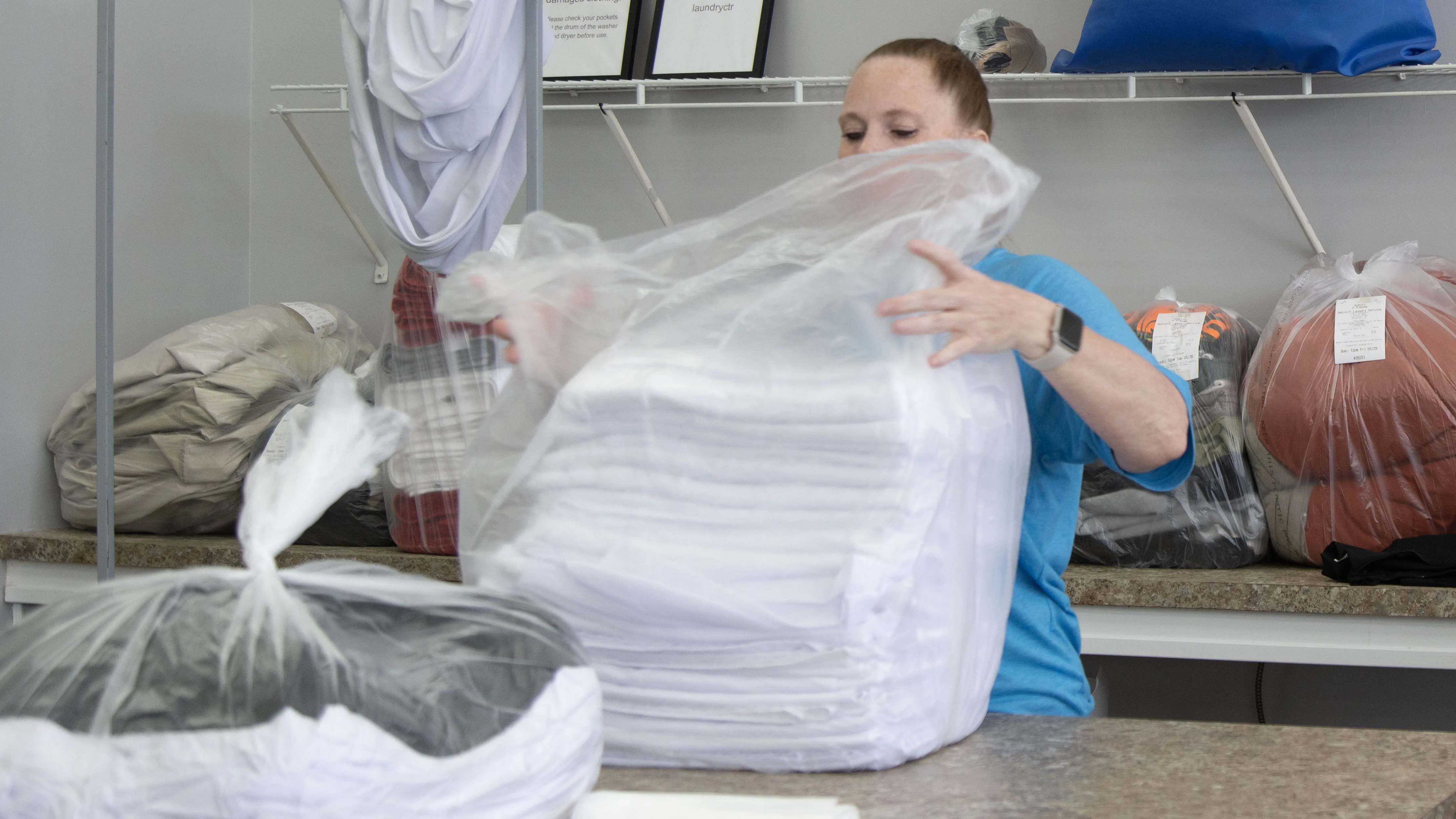 Attendant packaging a finished wash and fold order in protective plastic