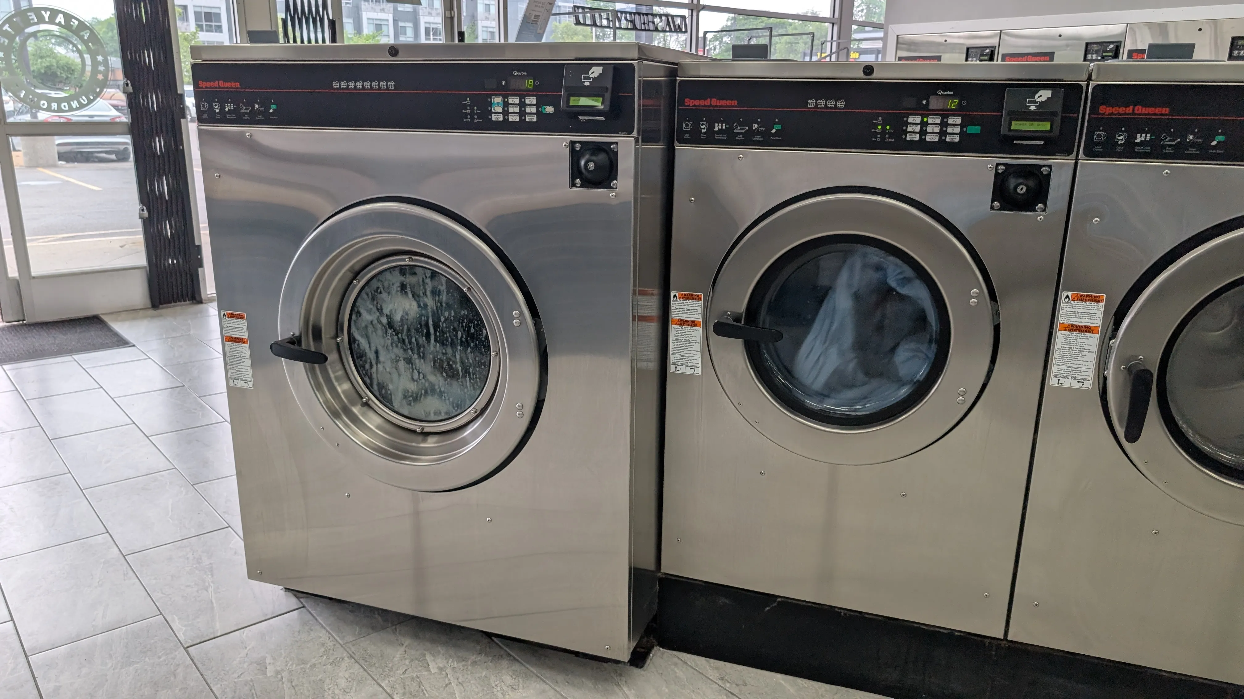 Speed Queen washers mid-cycle with suds visible through the door