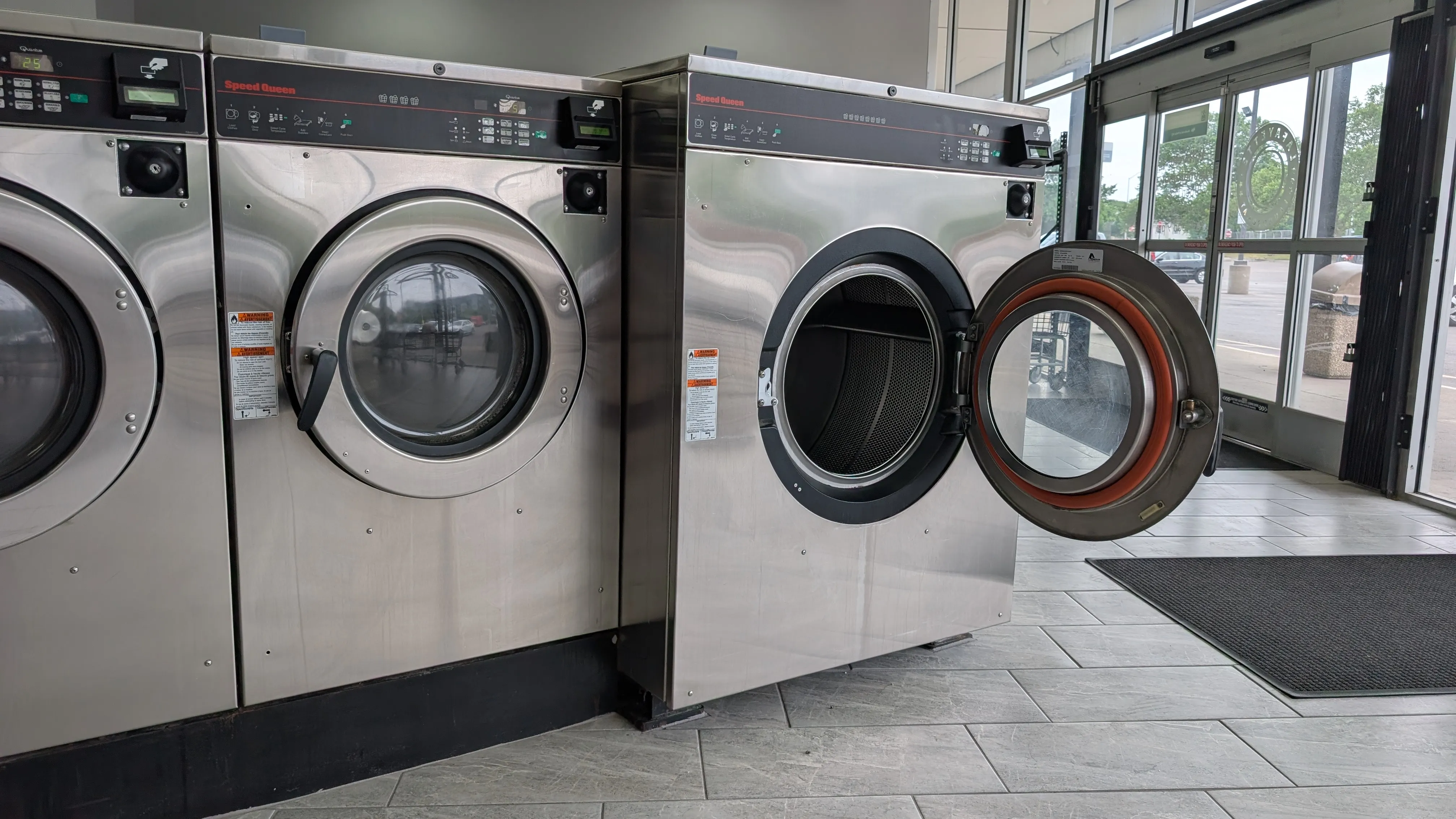 Speed Queen washers by the storefront entrance with a loading door open