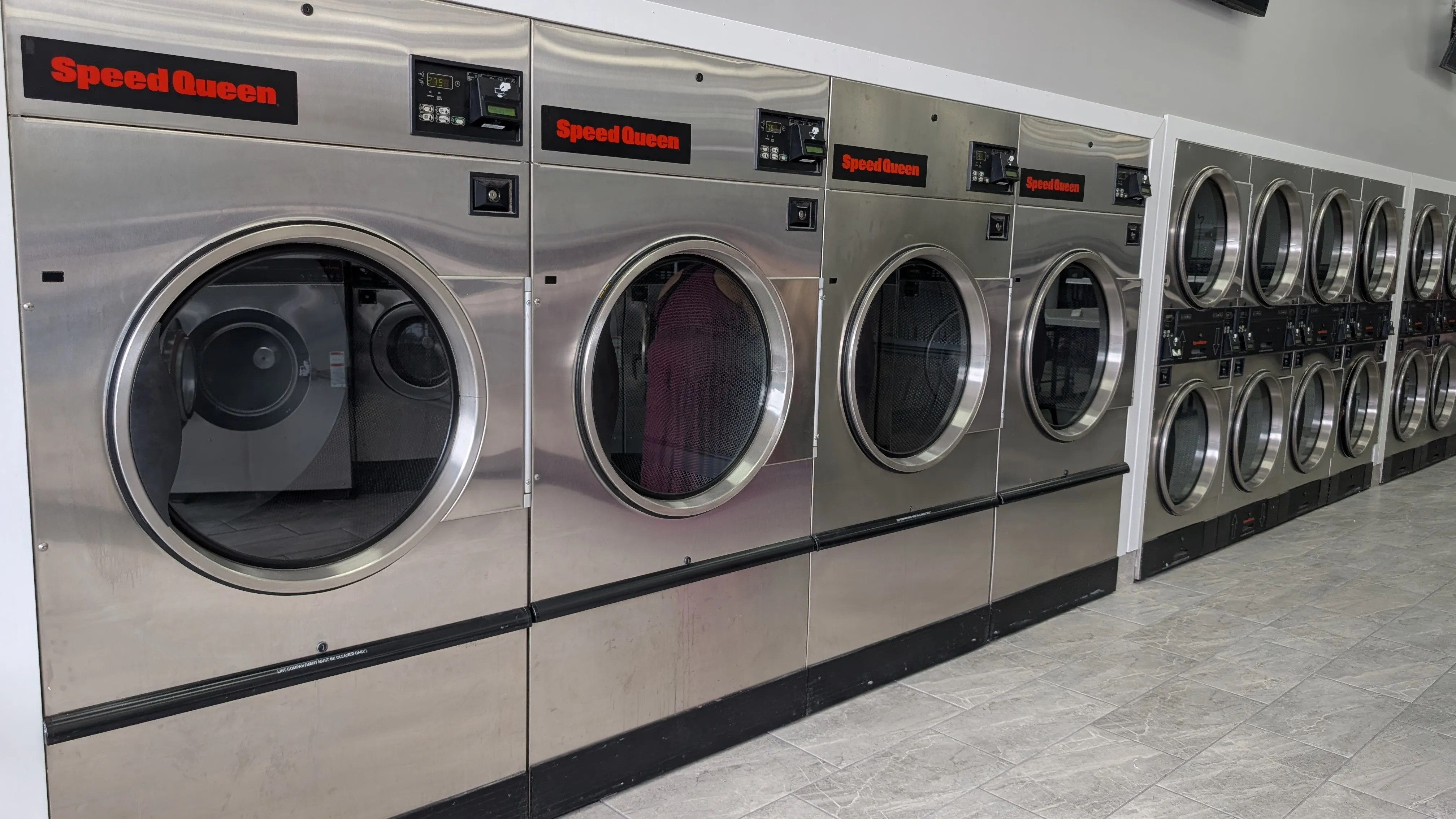 Speed Queen washers running with a row of dryers behind them