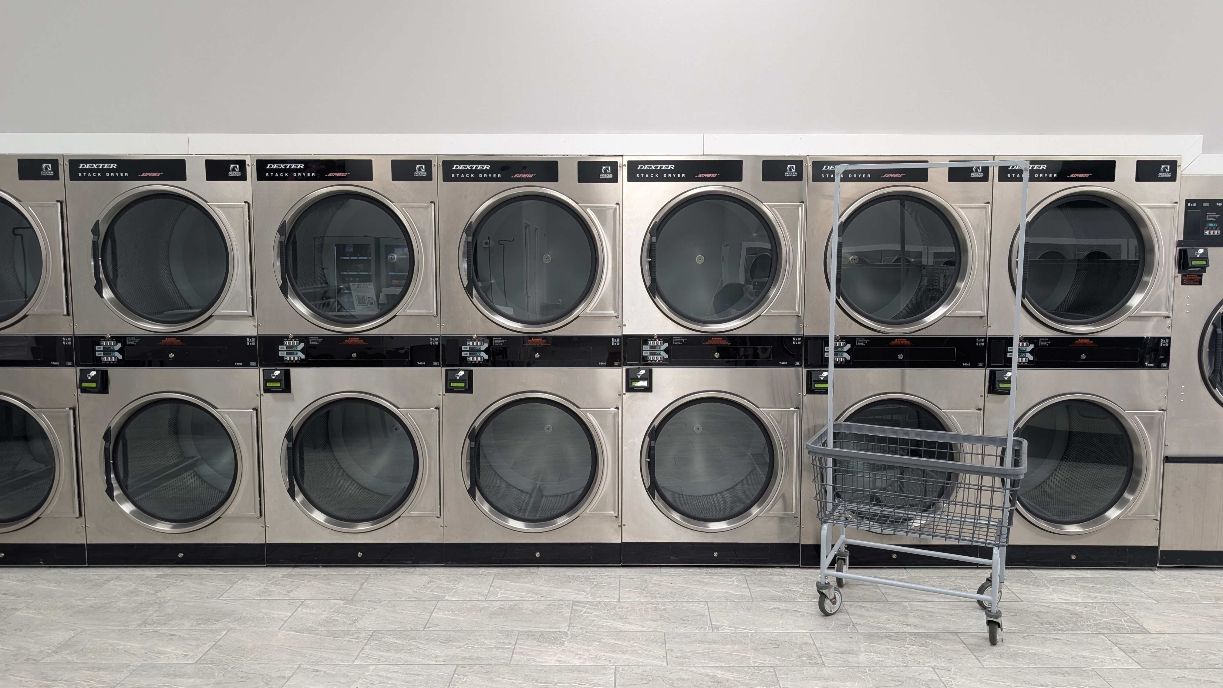 Row of Dexter stack dryers with a laundry cart at Lafayette Laundromat
