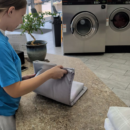 Attendant folding clean sheets after washing