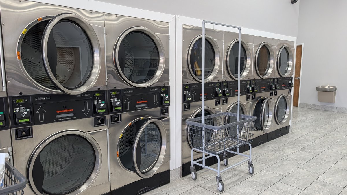 Stacked Speed Queen dryers and a rolling laundry cart