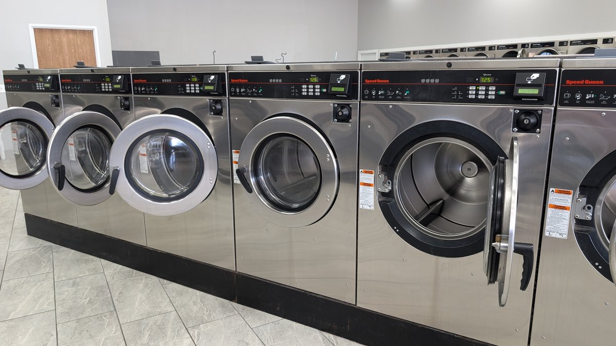 Row of Speed Queen washers with open doors on tile flooring