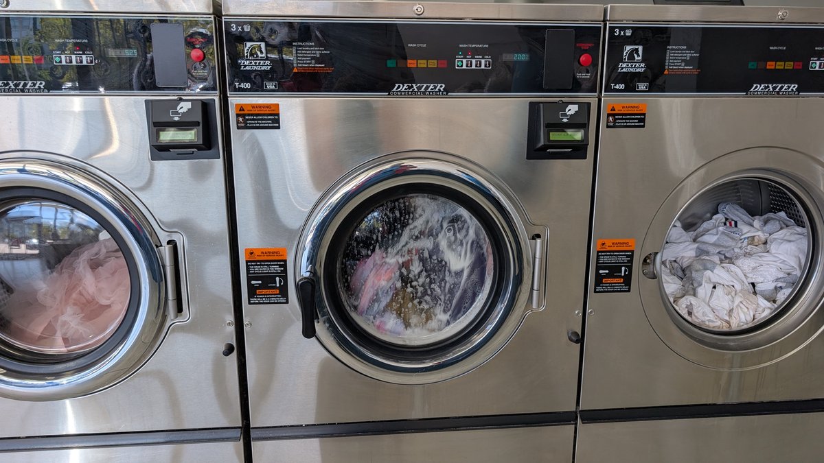 Dexter washers with laundry loads visible through the glass doors