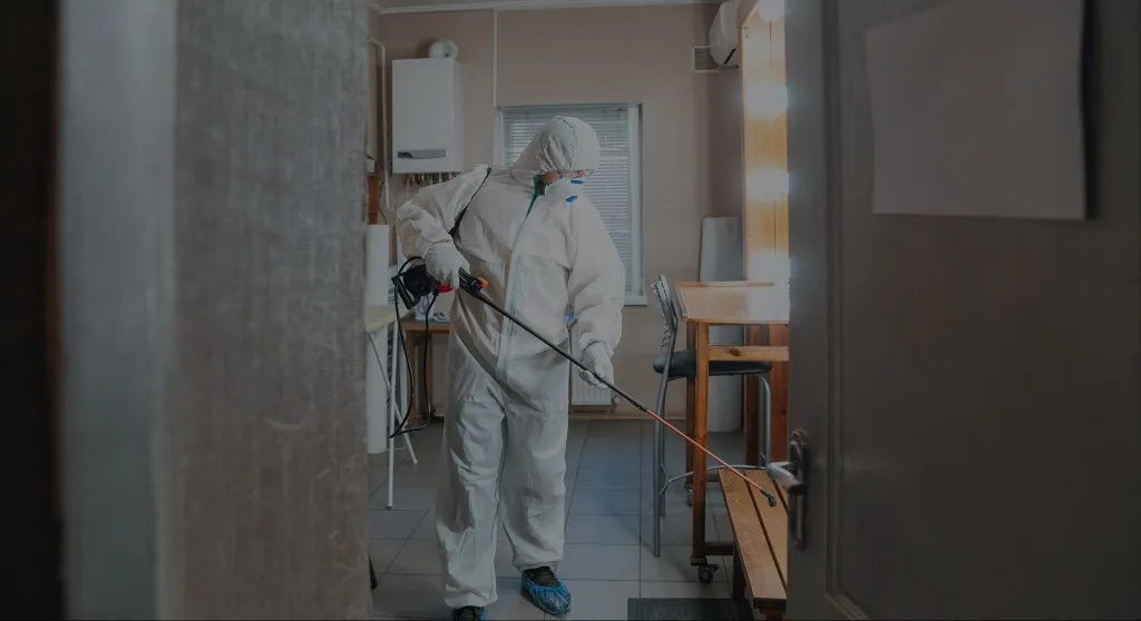 Technician in protective gear treating a property for mold