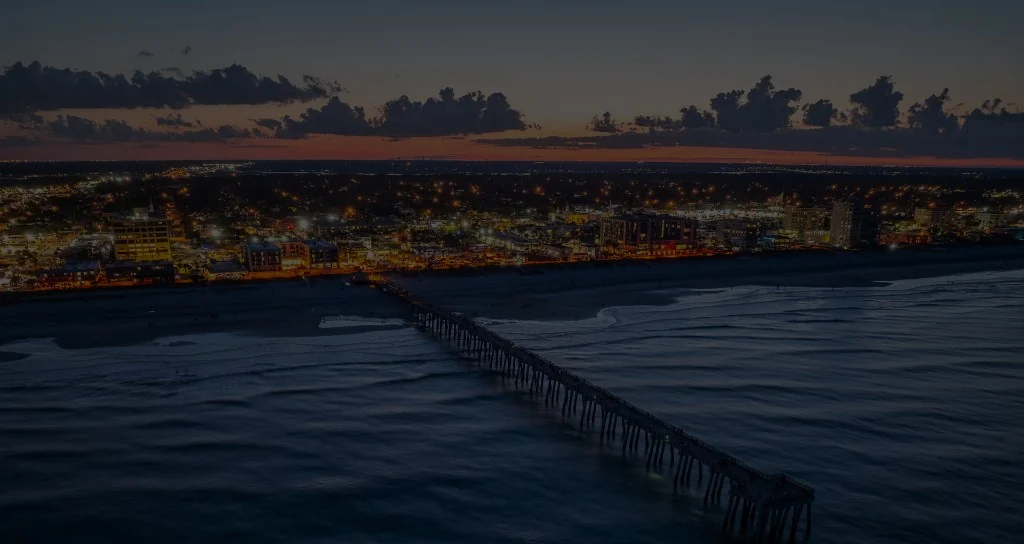 Aerial view of Jacksonville Beach pier and the illuminated coastline at dusk