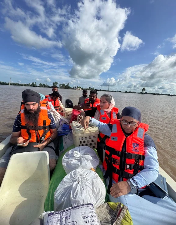 Flood-response volunteers travelling by boat in life jackets.
