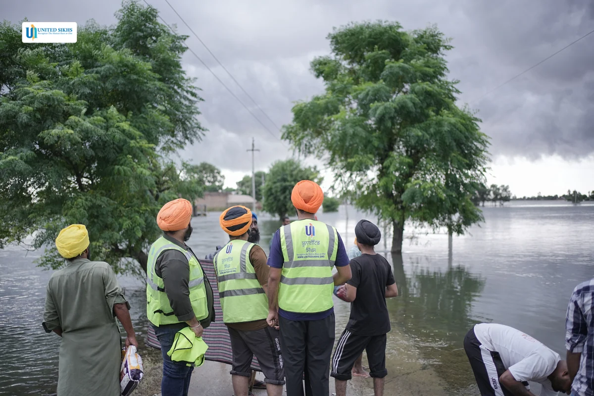 Relief volunteers in high-visibility vests beside floodwater.