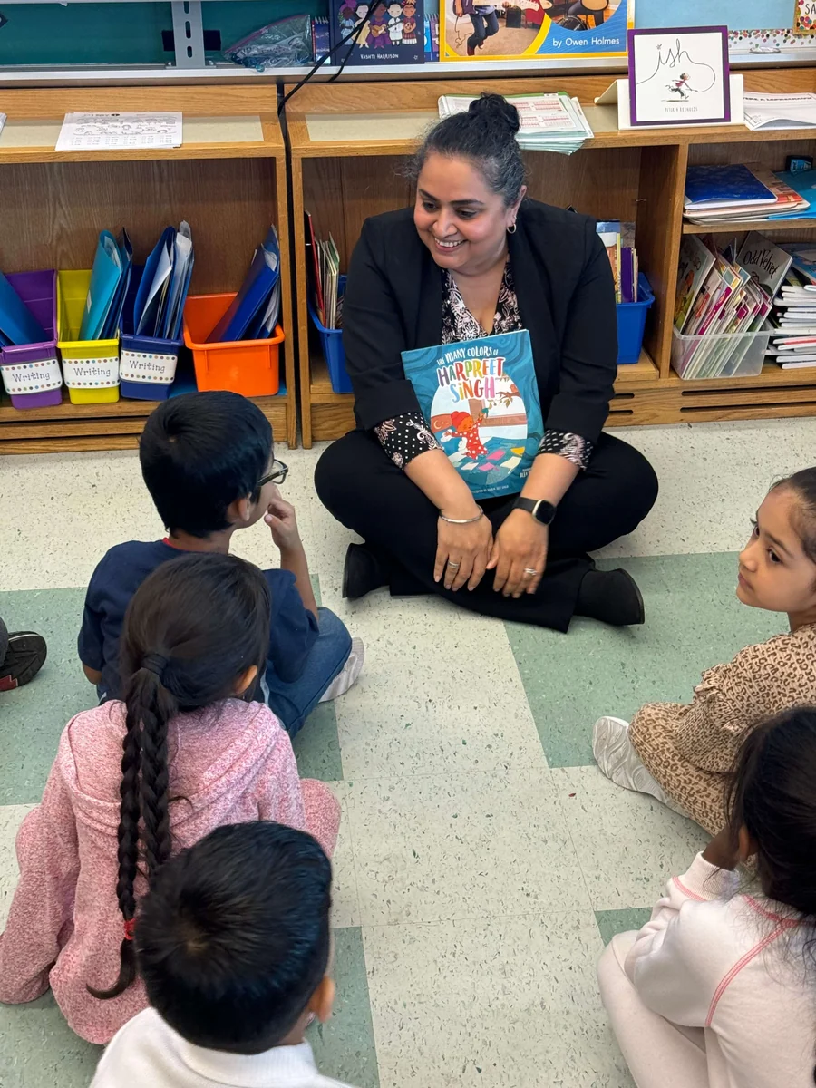 An educator reading with children seated in a classroom.