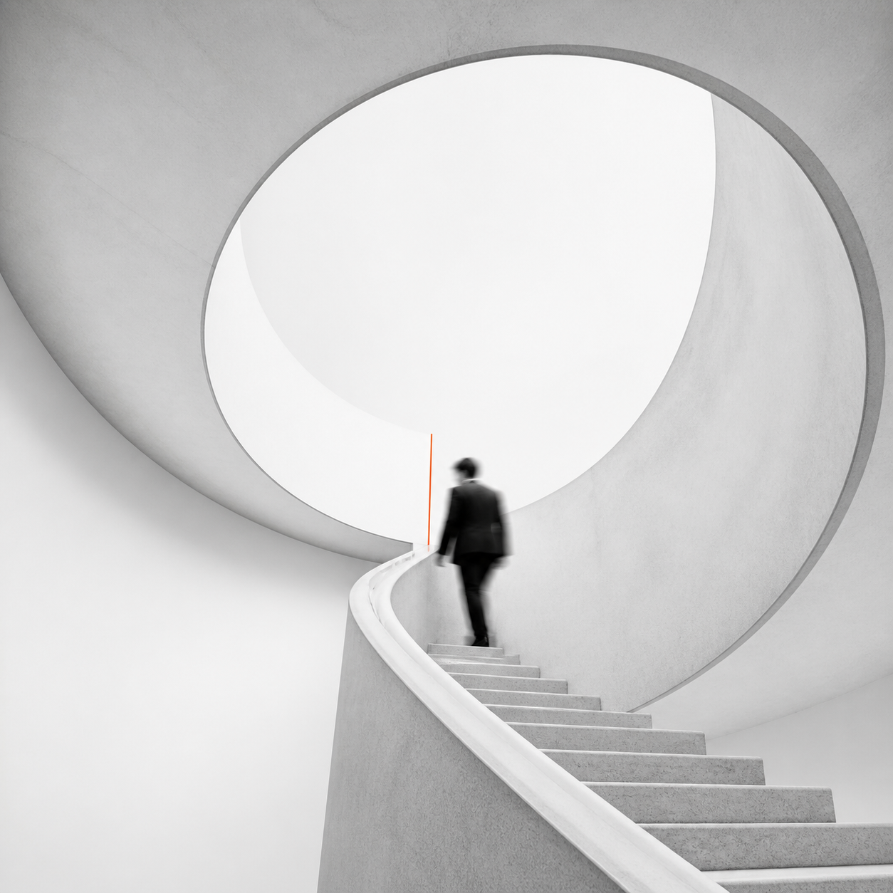Blurred figure of a person in a dark suit ascending a modern, curved white concrete staircase under a large circular skylight with smooth architectural lines.