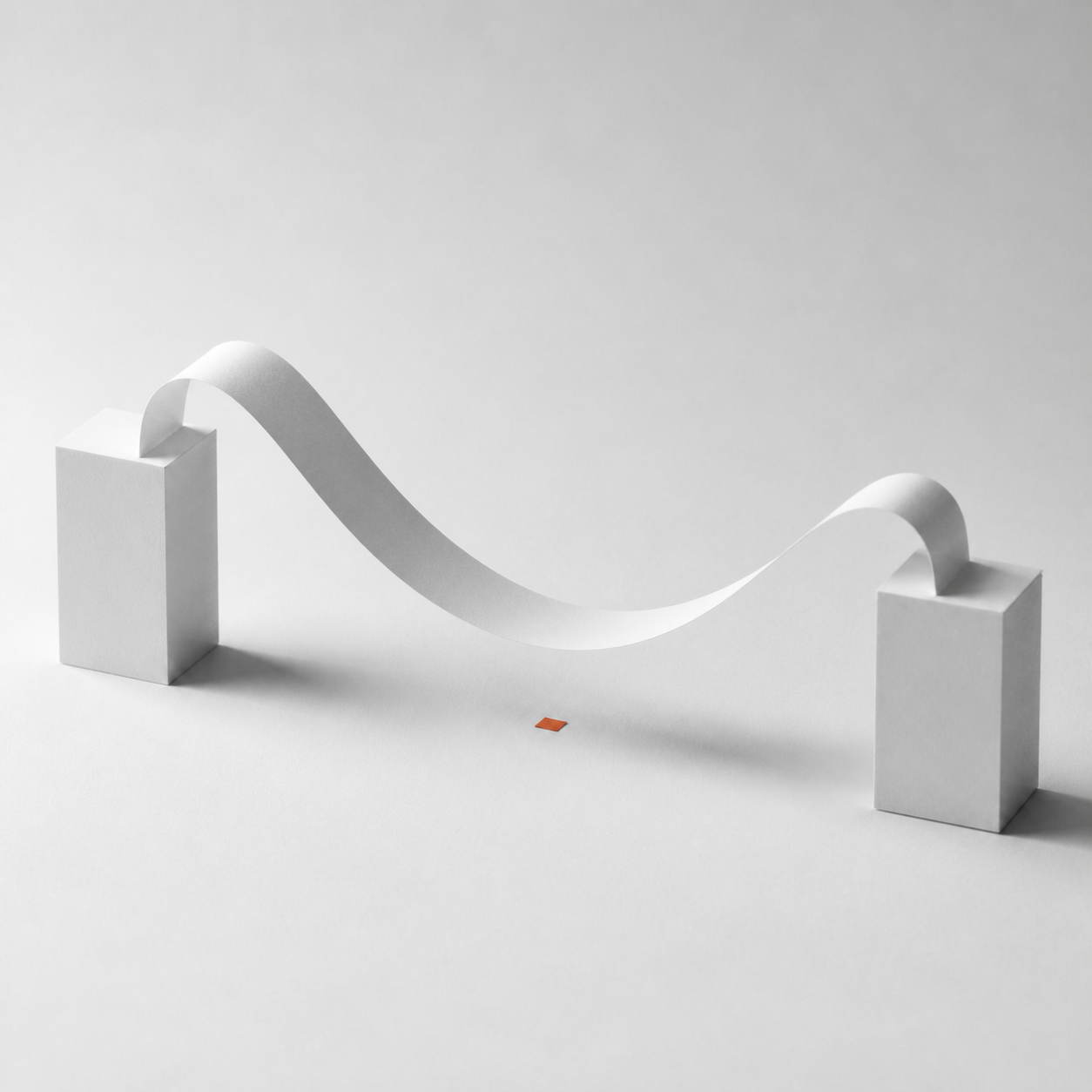 Minimalist scene with two white rectangular blocks connected by a curved white paper strip hovering above a small red square on a white surface.