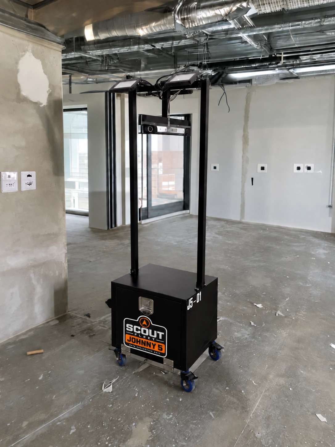 Scout JOHNNY5 unit at a construction site, with an orange compass logo and JOHNNY5 decal on its cabinet