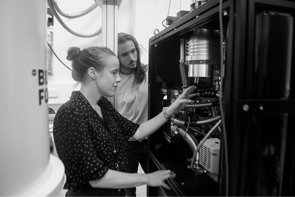 Photograph of a woman and a man looking into a quantum computer