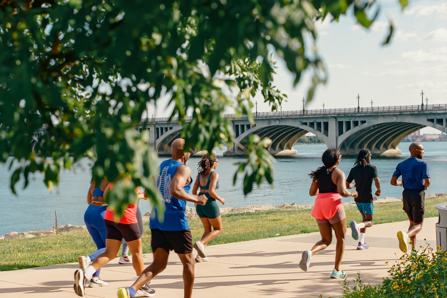A group of runners running along the water.