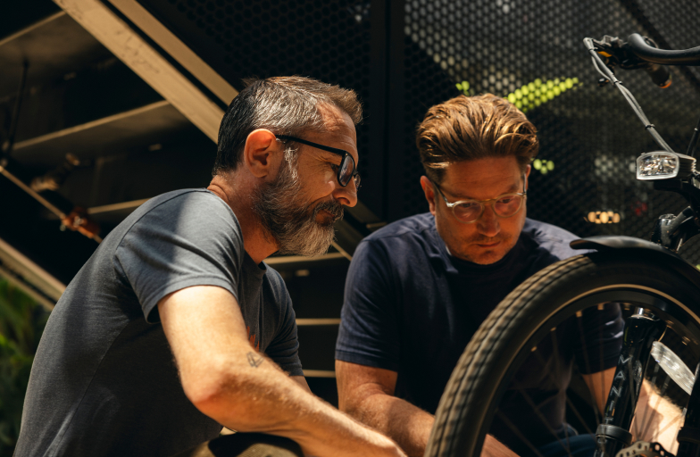 Two men working on the tire of a bike.