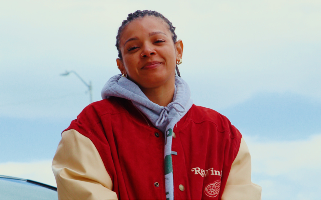 A photo of Erica Jackson wearing a red and tan jacket over a grey hoodie.
