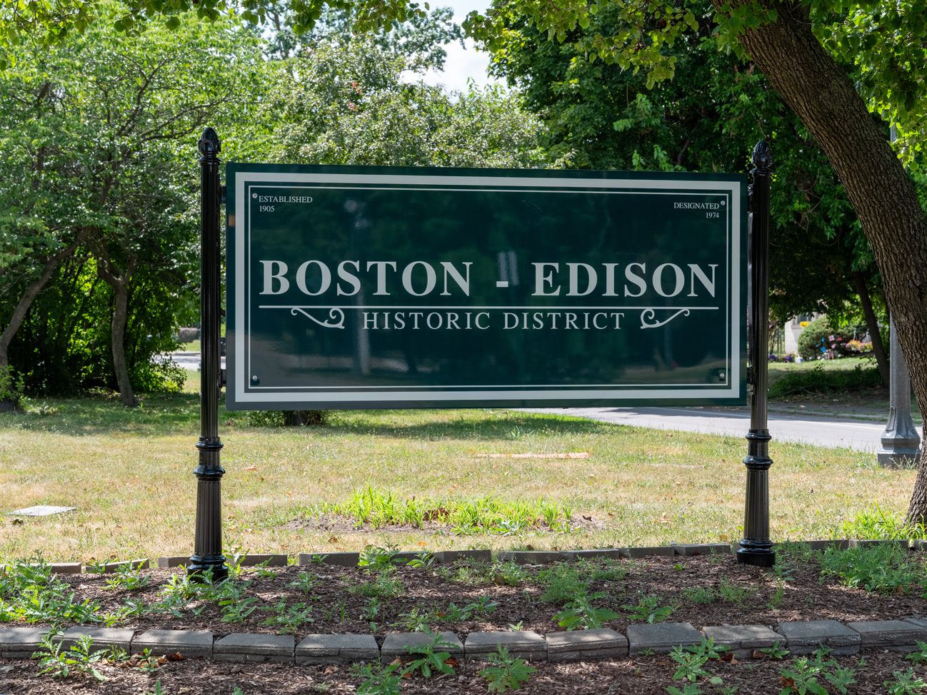 Green sign with white border and iron posts that says "Boston-Edison Historic District."
