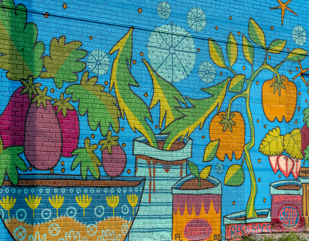 Brick wall mural of various plants including fruits and vegetables.