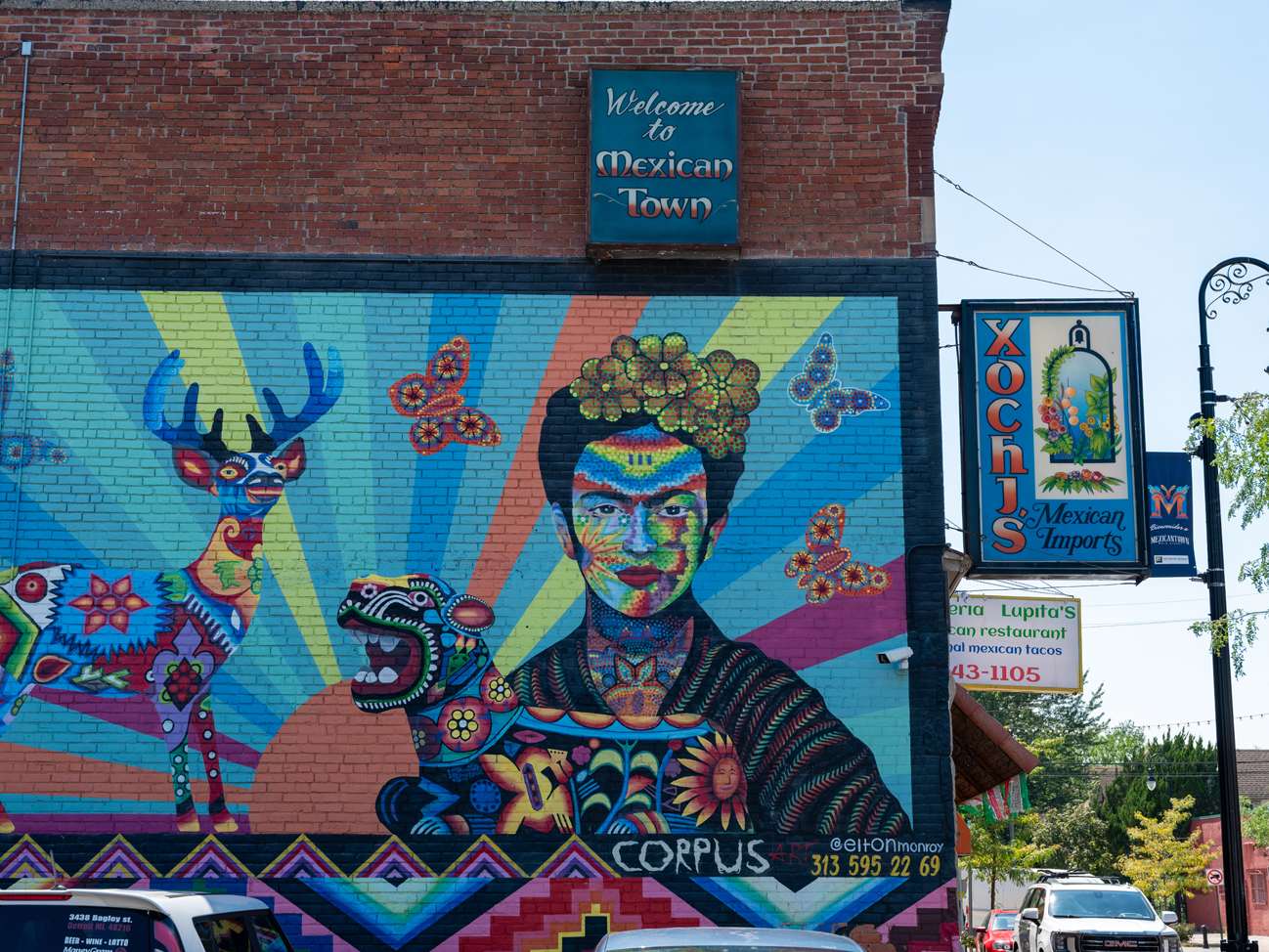 Colorful mural of Frida Kahlo holding a dog-like animal, surrounded by butterflies and a deer.