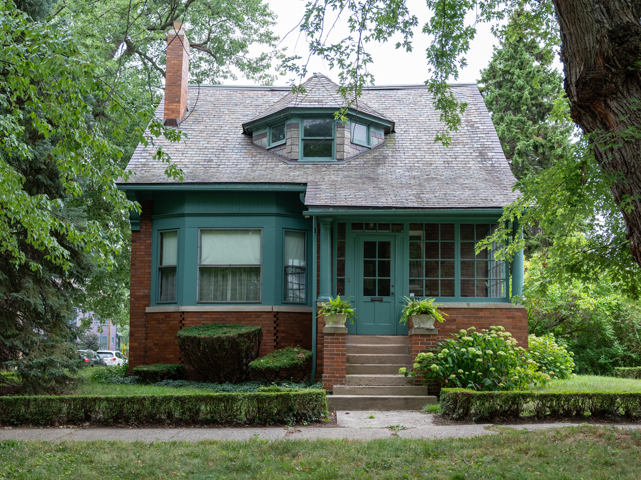 Photo of a historic green and red brick home.