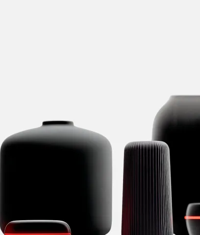 A group of modern, matte black ceramic vases of varying shapes and sizes arranged close together against a light background.