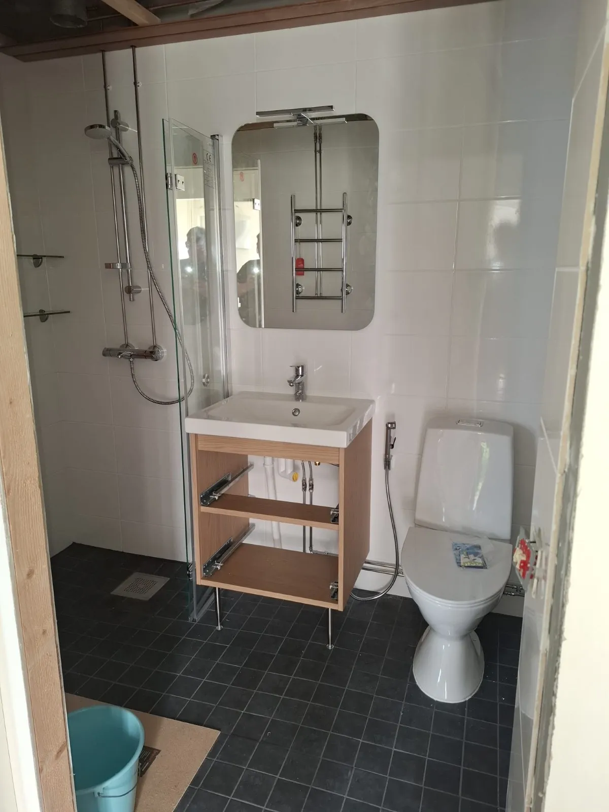 Kylpyhuone, johon on asennettu suihku, pesuallas ja wc-istuin.