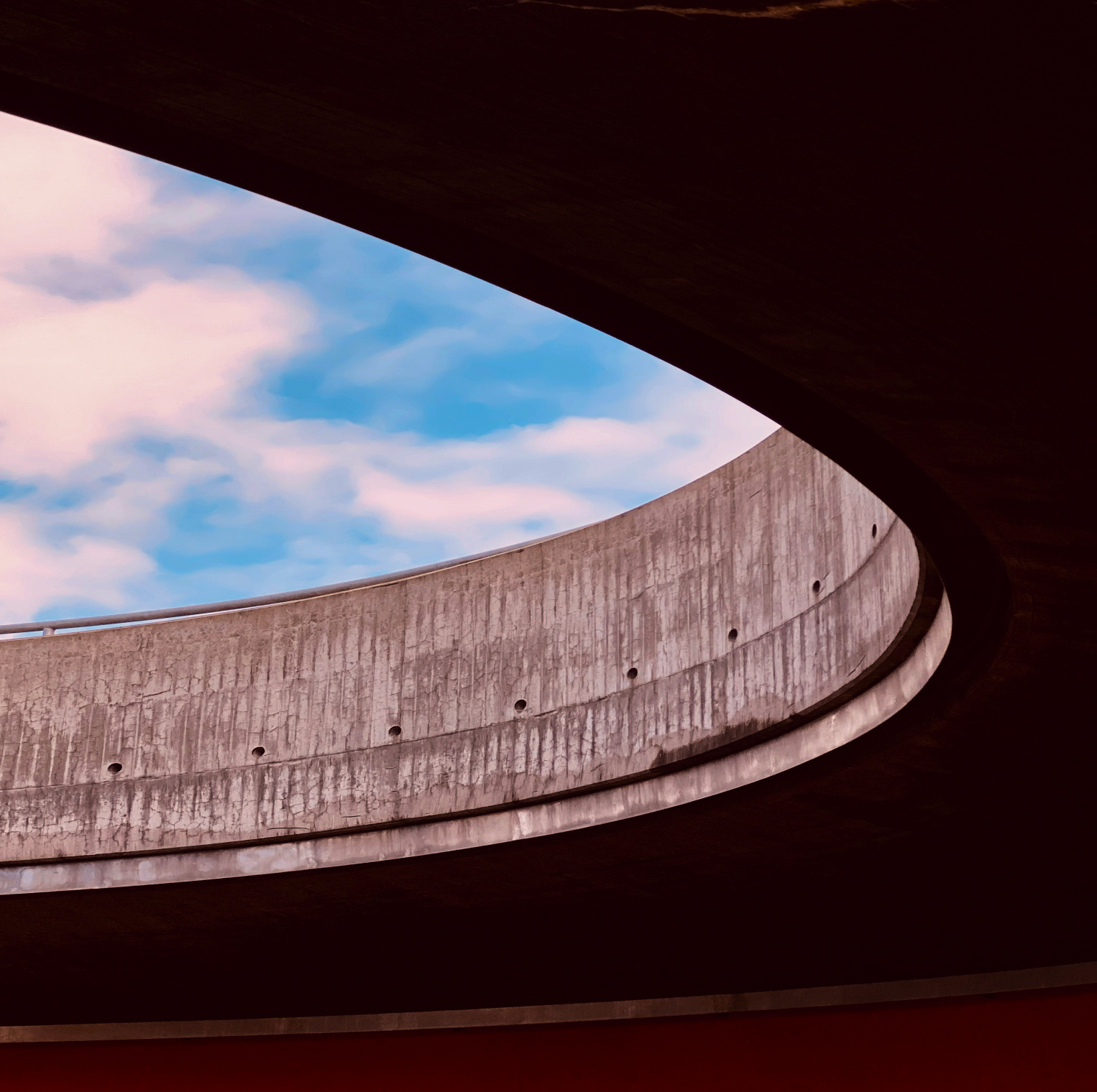 The curved white facade of a modern building against a blue sky