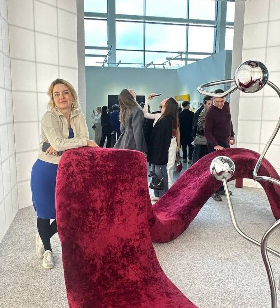 A guest pausing beside a red velvet sculptural seat while others move through the exhibition