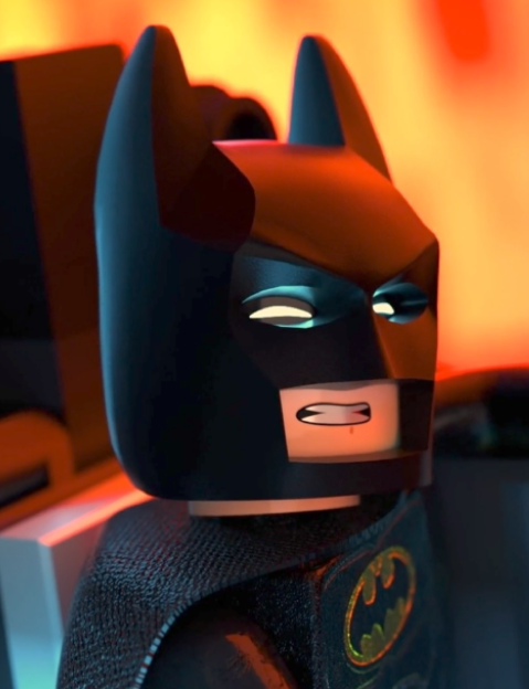 Close-up of a LEGO Batman minifigure with a black mask and cape, glowing eyes, and a grimacing mouth, set against a blurred orange background.