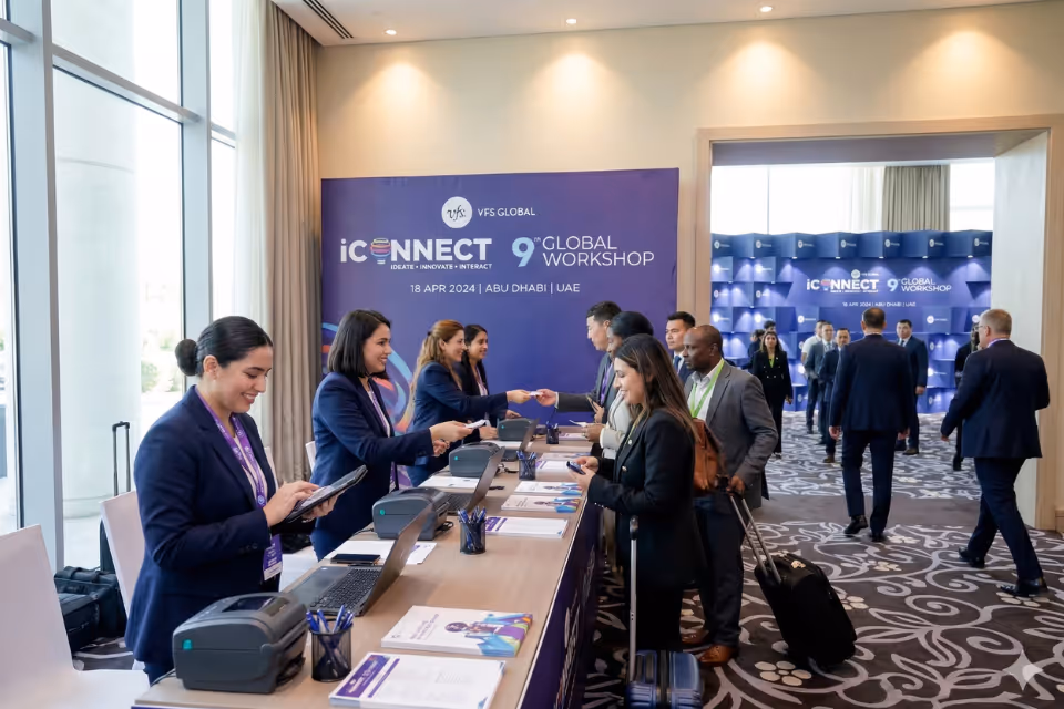 Conference registration desk with staff assisting attendees, featuring event signage and branded registration counters.