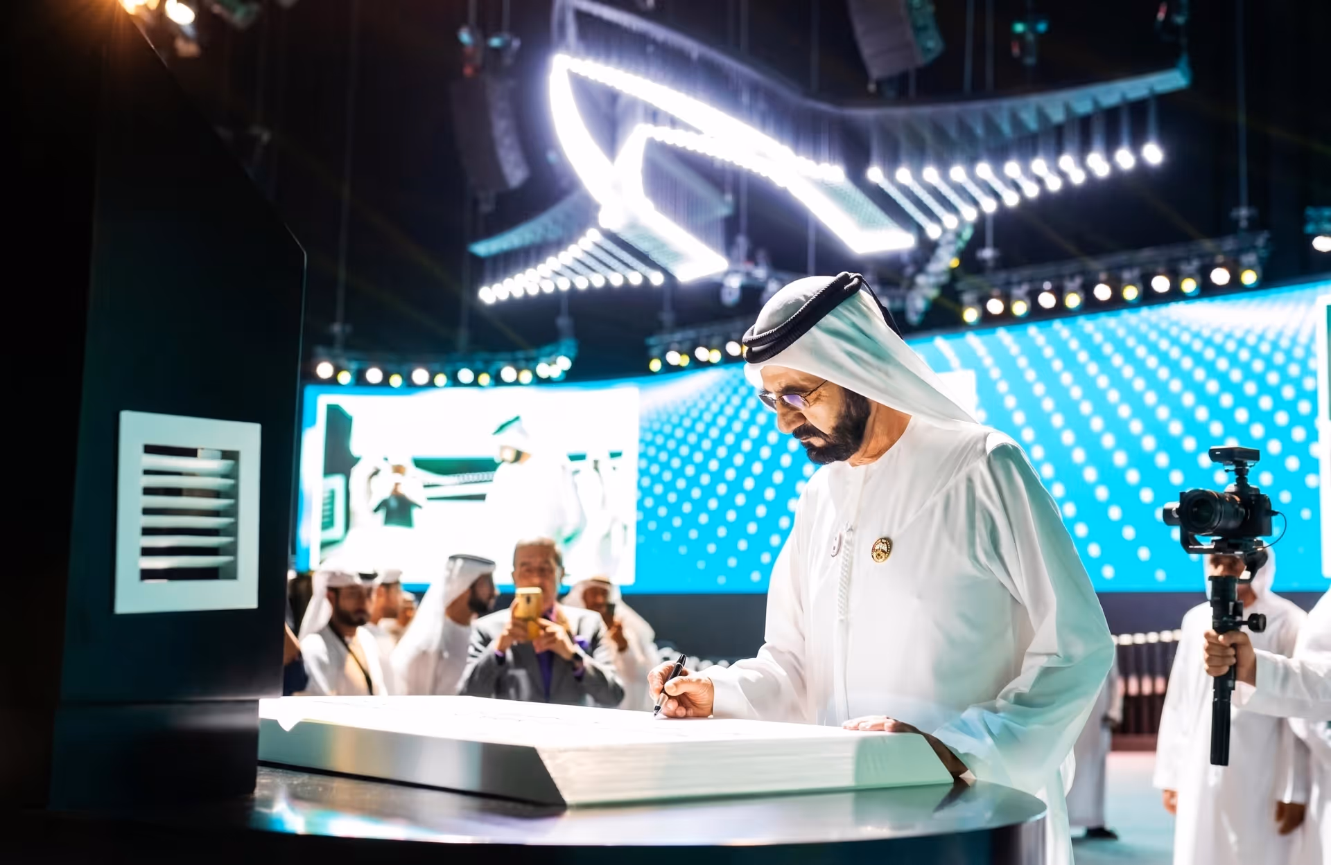 UAE leader signing at a high-tech event.