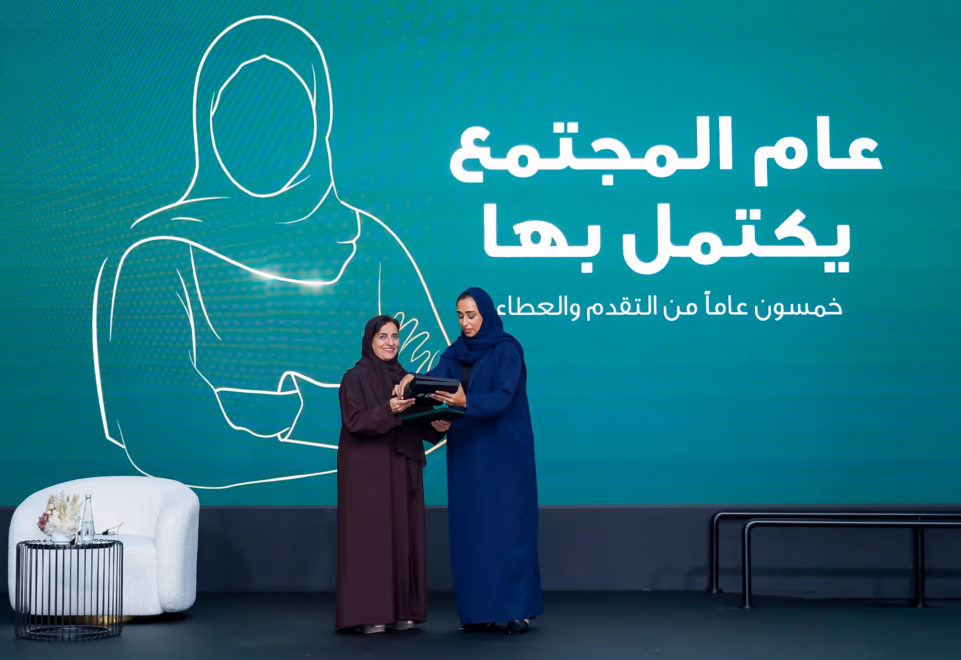 Women presenting an award at a Saudi cultural event.