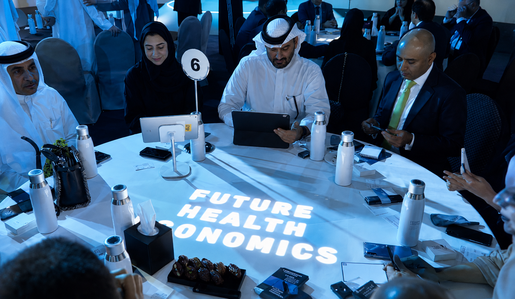 Participants at a table during a "Future Health Economics" workshop at a Dubai healthcare event.