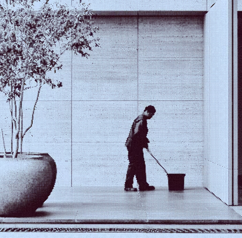 Janitor mopping floor near a large potted plant in a minimalistic indoor space.