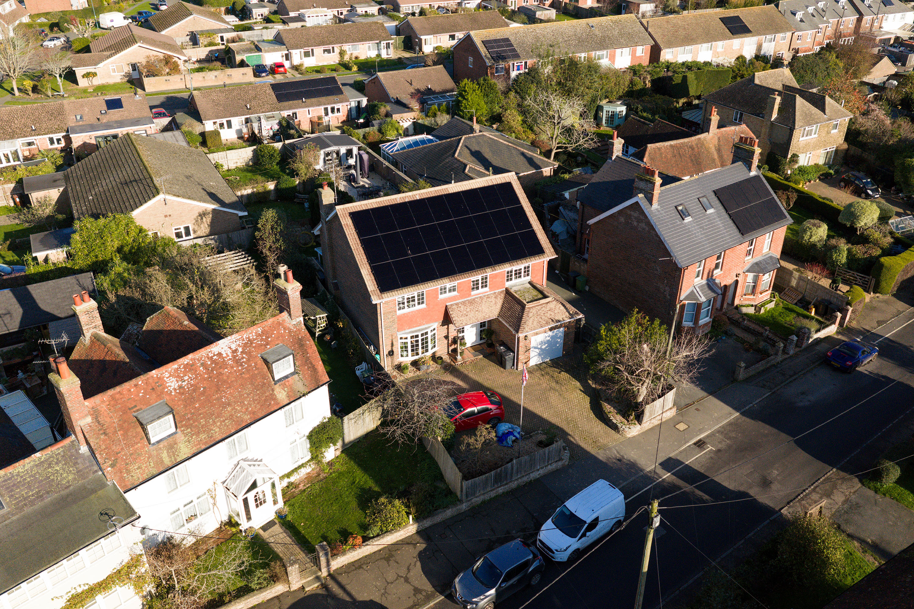 Aerial view of a house with a completed solar panel installation across the main roof slope.