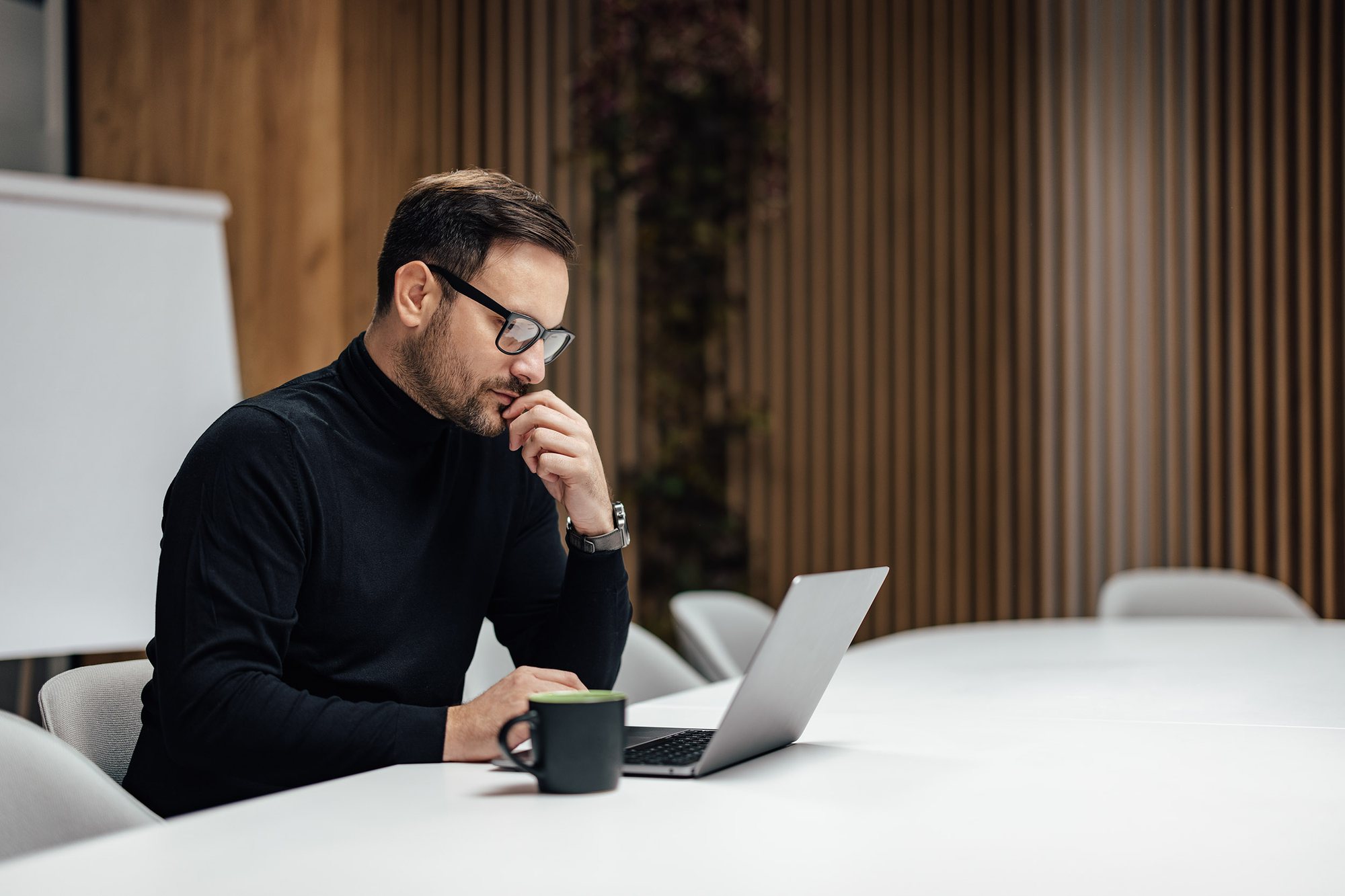 Executive working at a laptop in a boardroom, photographed on location