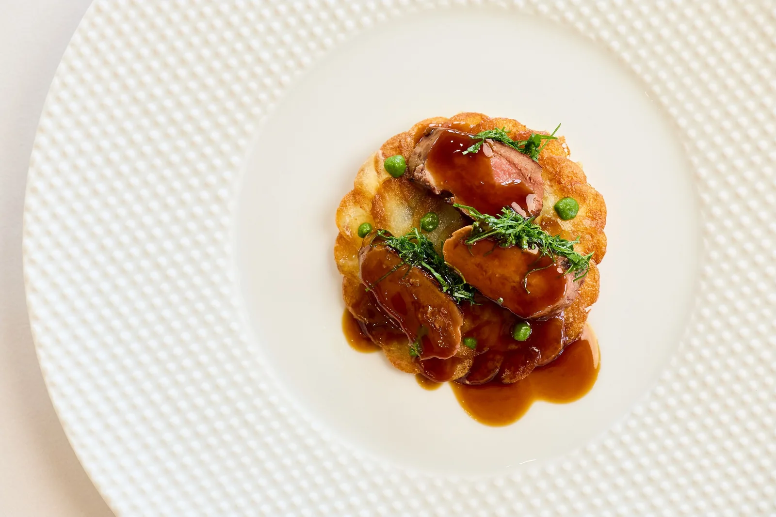 Duck on a potato galette seen from above, food photography for a fine dining restaurant