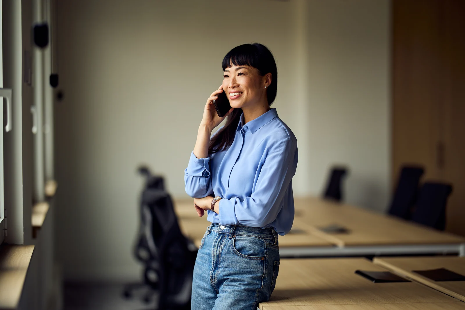 Manager on a call by the window of a meeting room, business portrait for a professional services firm