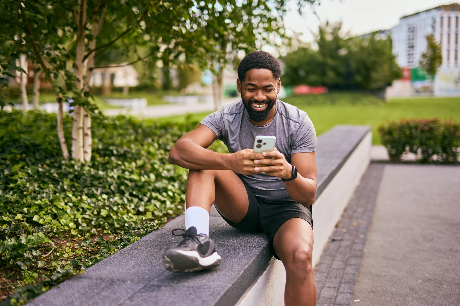 Runner checking his phone in the park, lifestyle photography for a brand campaign