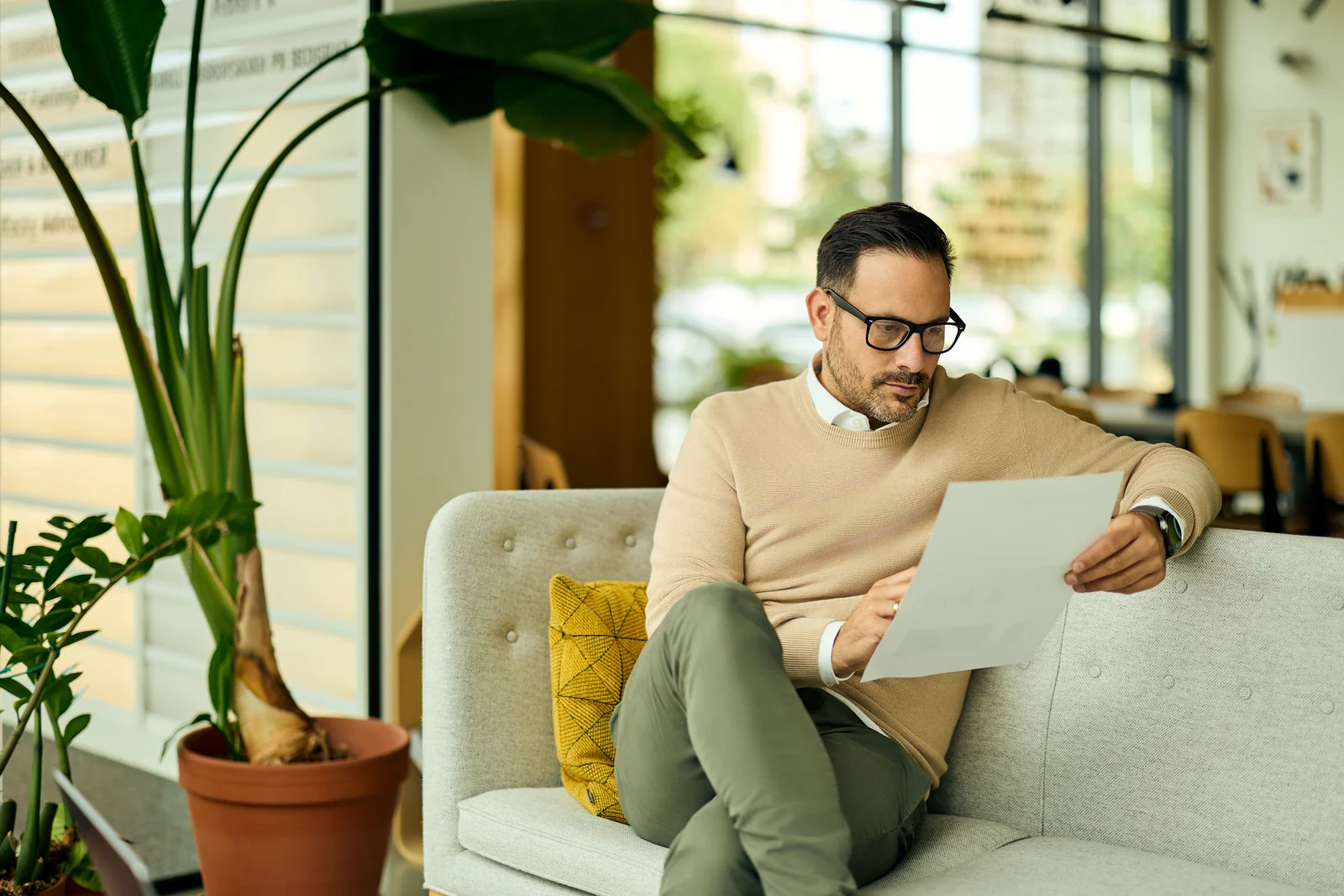 Executive reading a document on the lounge sofa, business portrait for a professional services firm