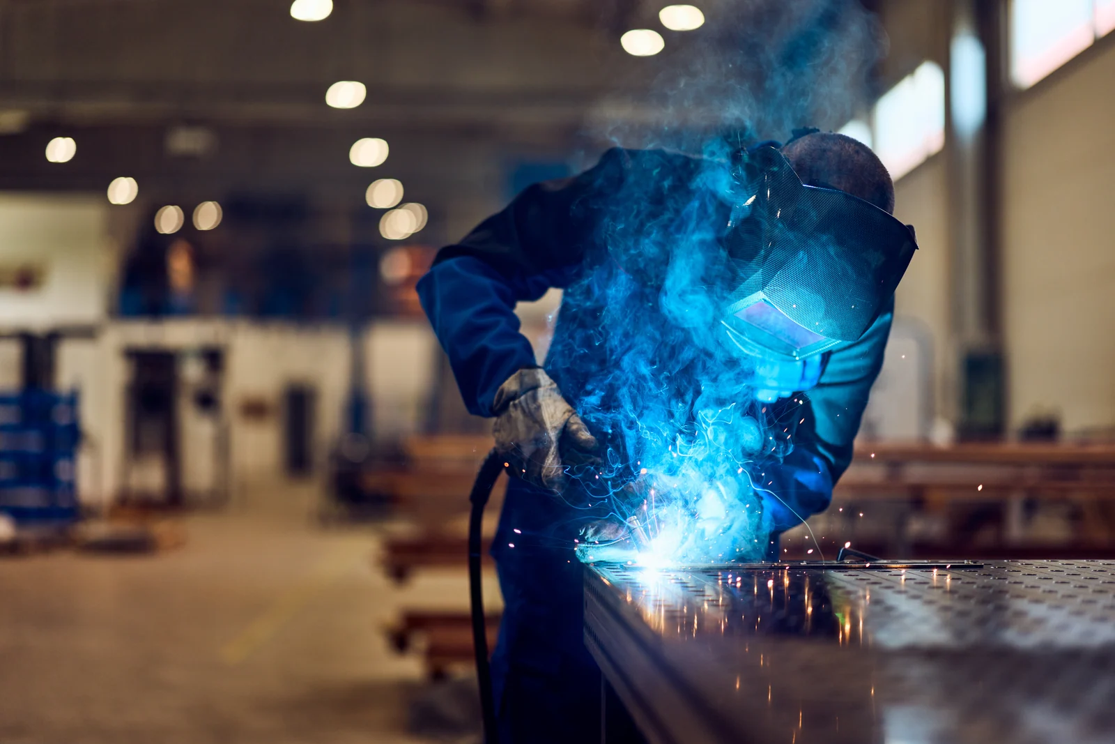 Welder at the bench in the fabrication hall, brand photography for a manufacturer