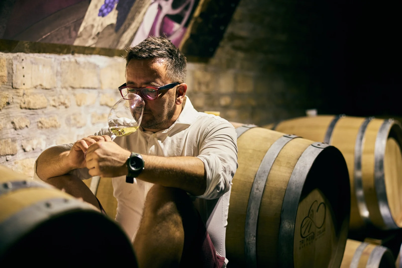 Winemaker tasting a white from the barrel, brand photography for a winery