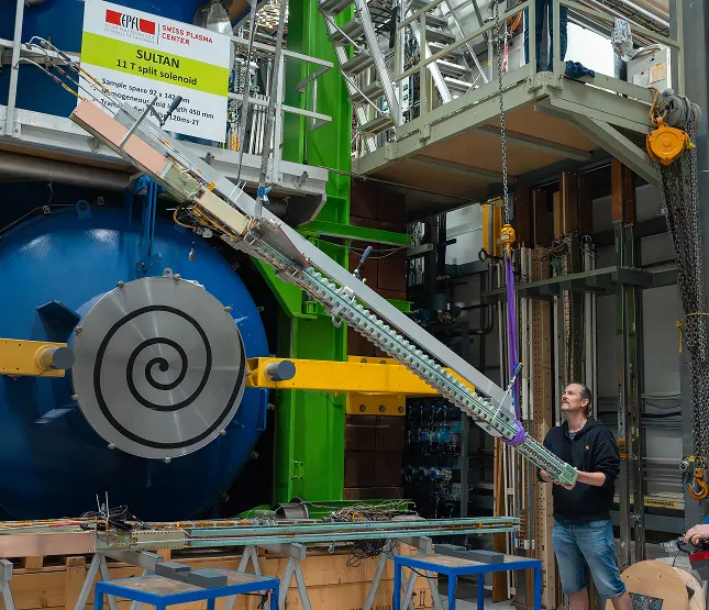 A man adjusting a large heavily-engineered object in an industrial space.