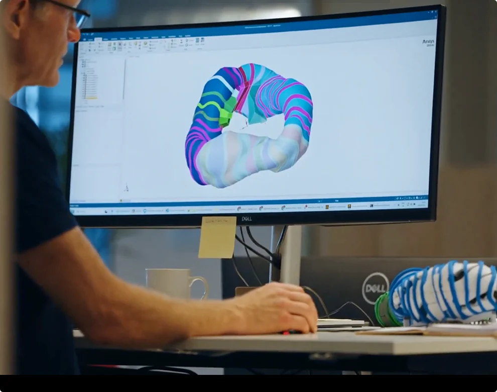 Someone at their desk on a computer, working on a design of a fusion power plant.