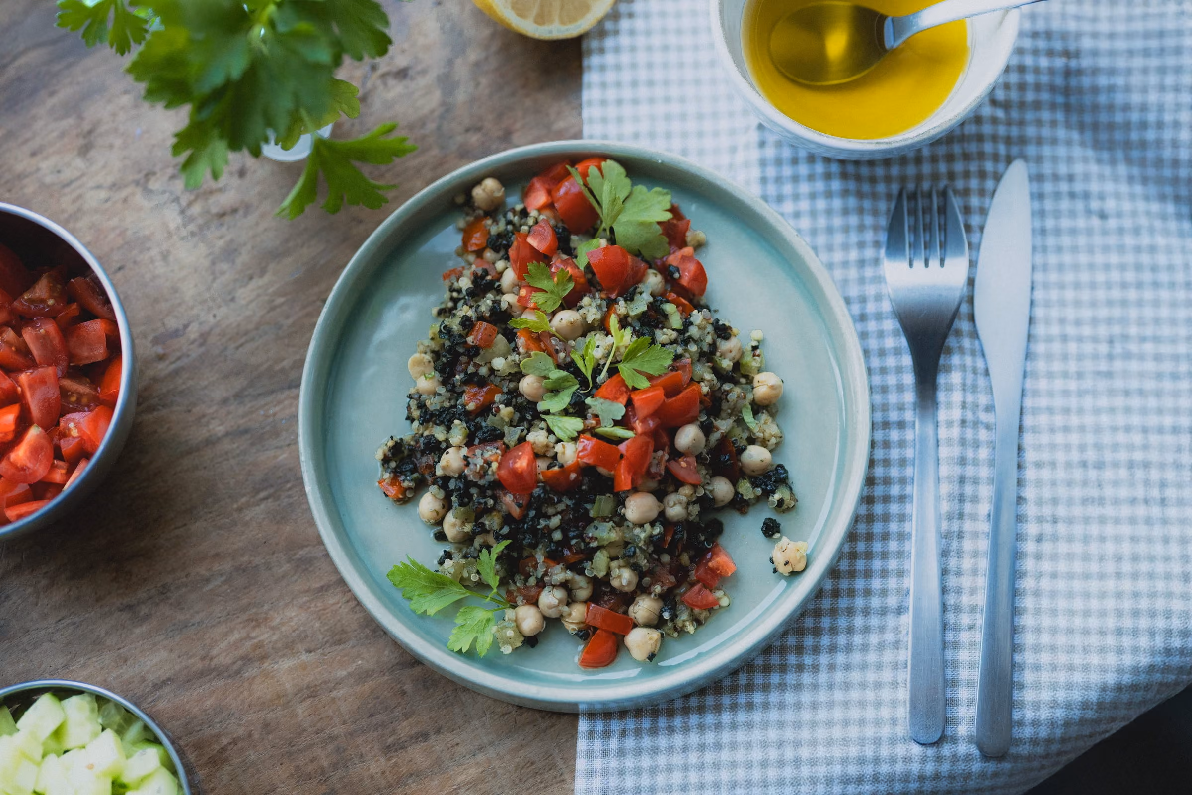 Assiette de taboulé aux pois chiches, tomates et persil frais, sur une nappe à carreaux bleue