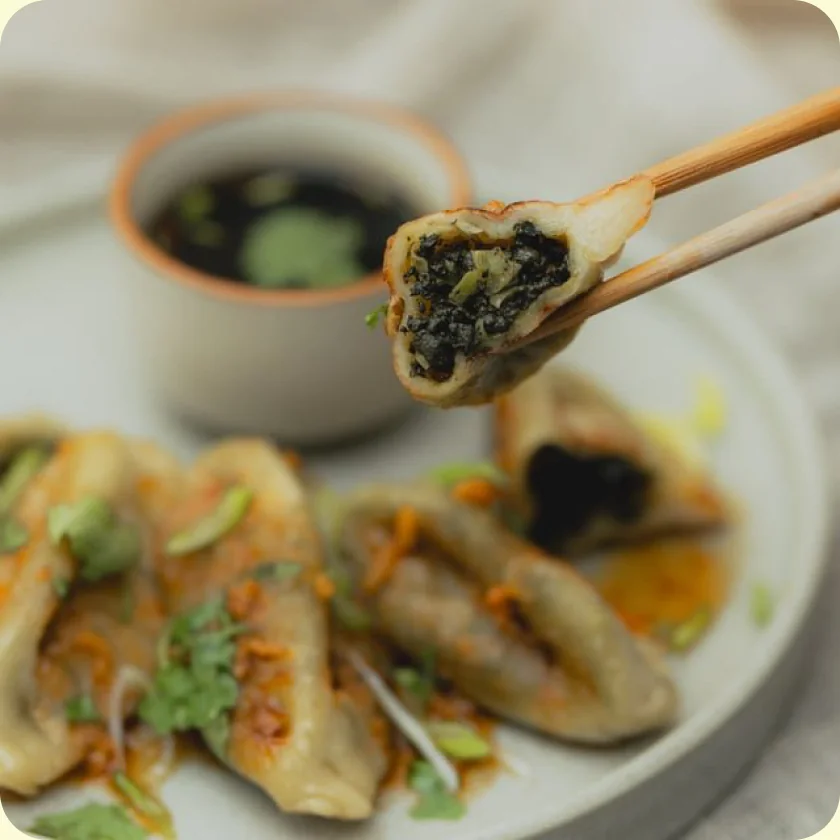Gyoza garni au Edo saisi à la baguette, au-dessus d'une assiette