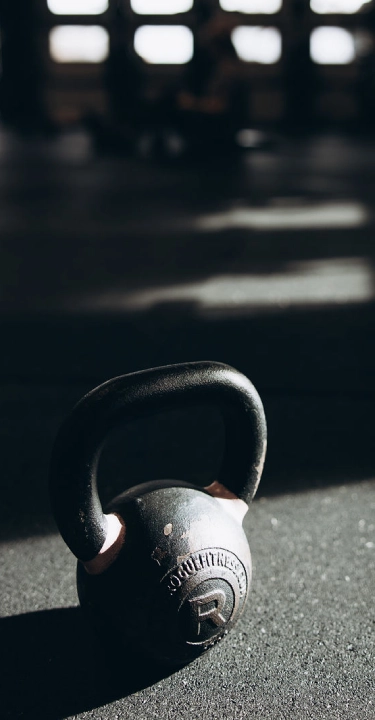 Kettlebell resting on a gym floor in dramatic natural light.